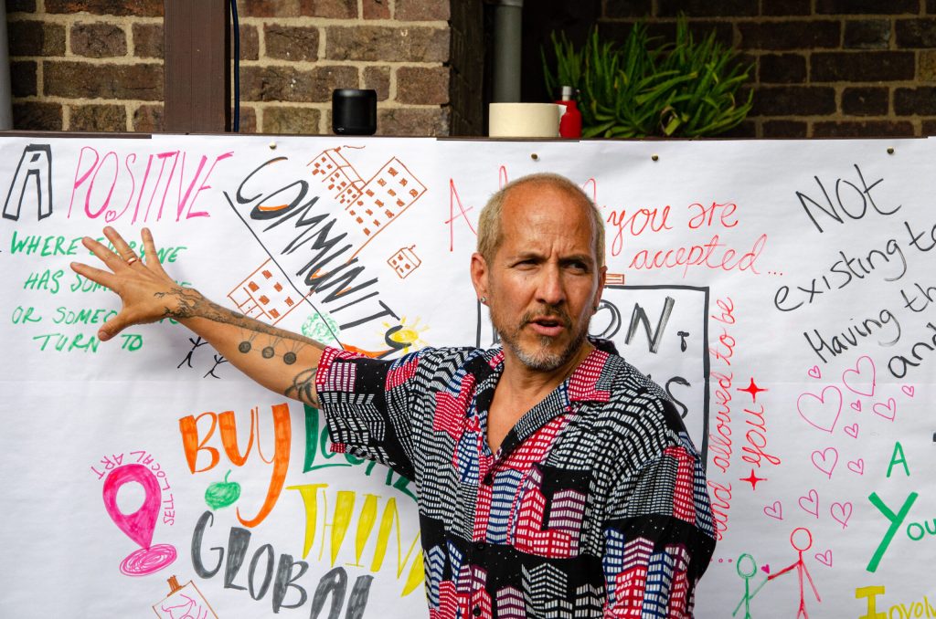 A man pointing to a large piece of paper with writing on it