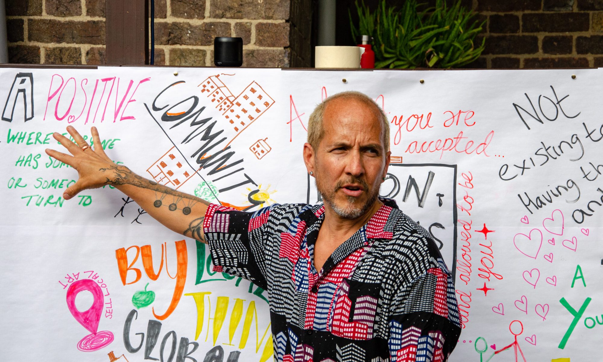 A man pointing to a large piece of paper with writing on it