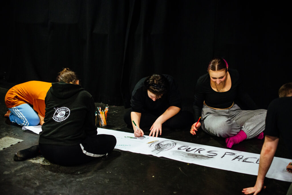 A group of people writing on a long sheet of paper