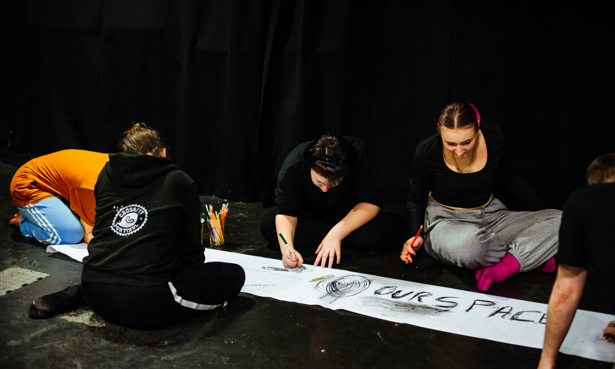A group of people writing on a long sheet of paper