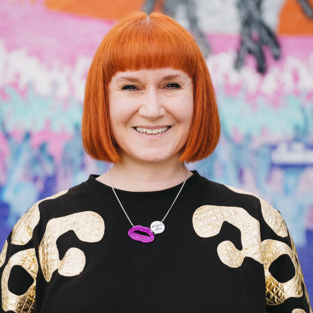 A smiling woman in front of a colourful background