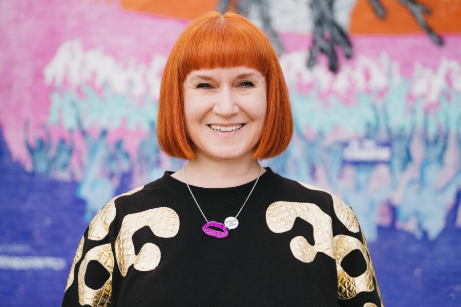 A smiling woman in front of a colourful background