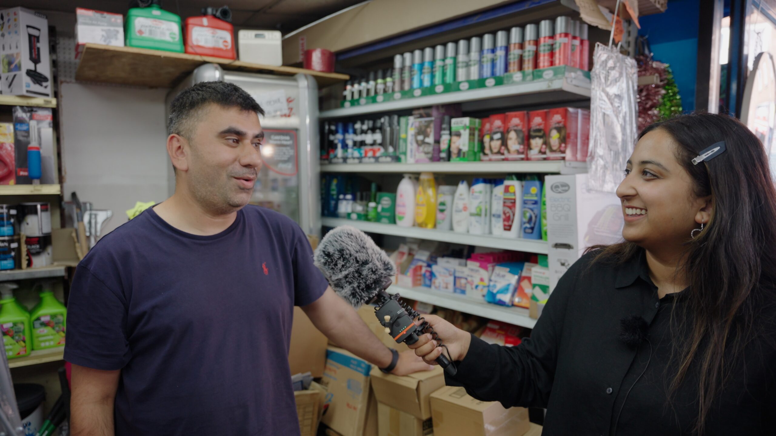 Interviewer with microphone speaking to Luton shop owner
