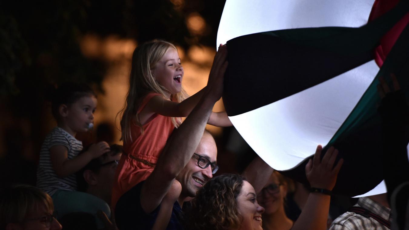 Young girl sits on a man's shoulders to touch an illuminated ball