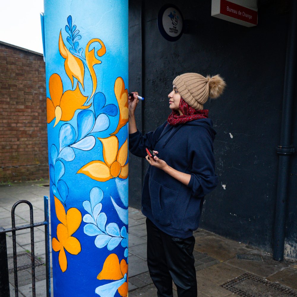 Woman painting a pillar outside