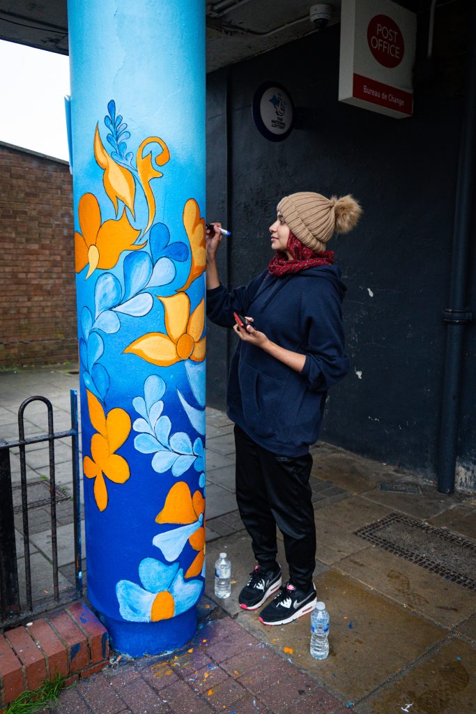 Woman painting a pillar outside