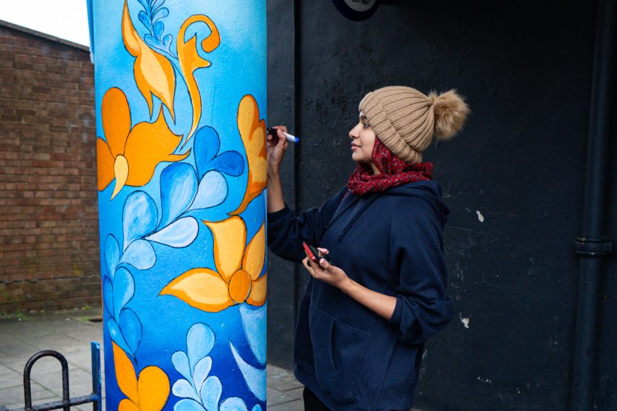 Woman painting a pillar outside