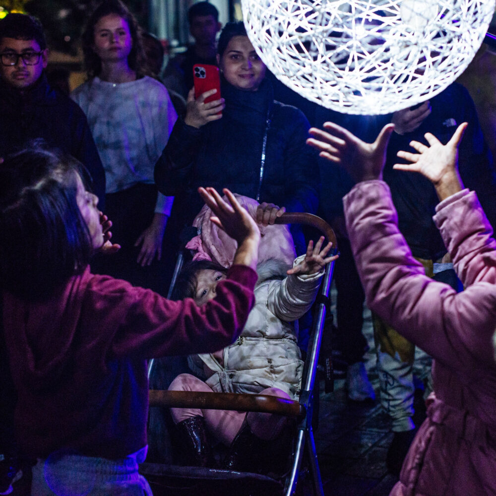Young people raise their hands towards an illuminated orb
