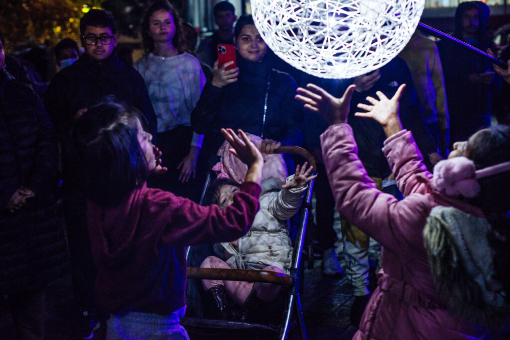 Young people raise their hands towards an illuminated orb