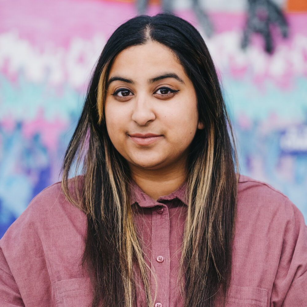 A woman standing in front of a colourful background