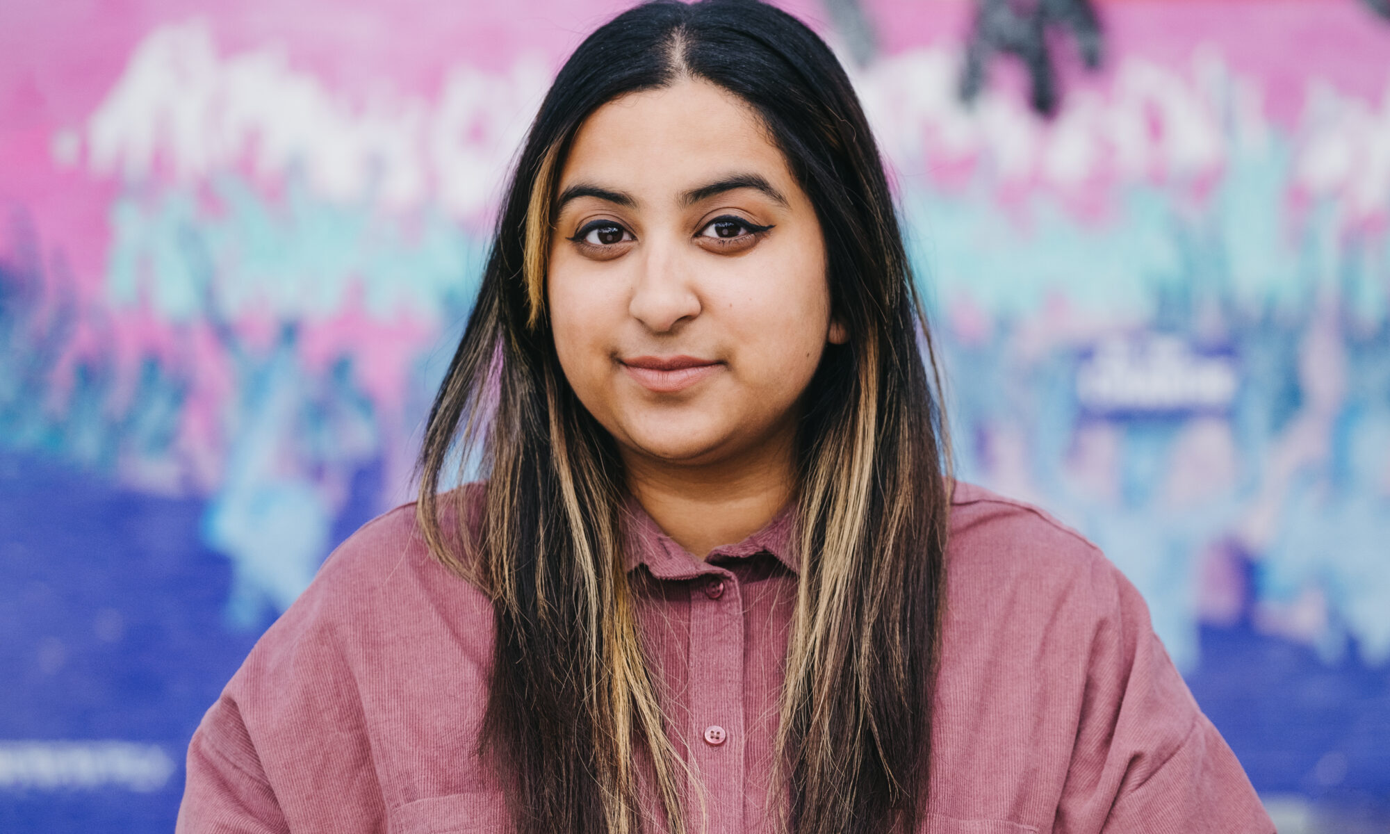 A woman standing in front of a colourful background