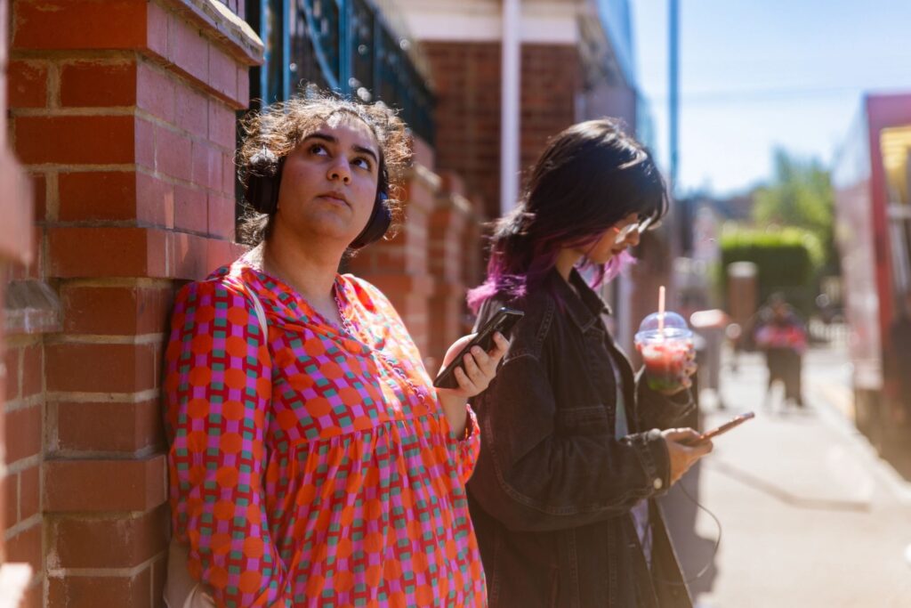 Two women listening to headphones on a high street