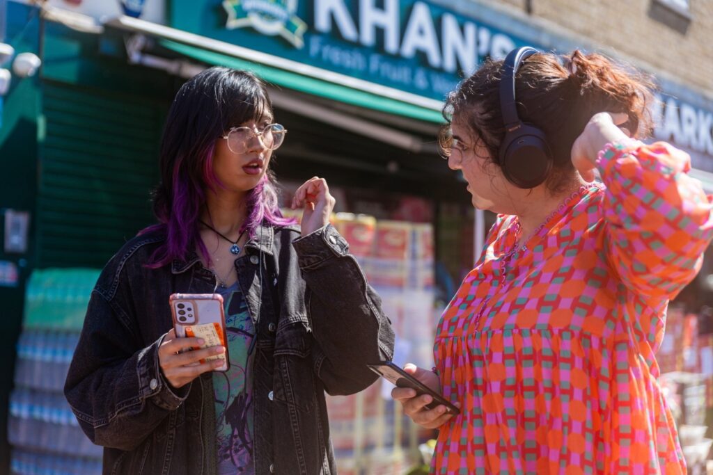 Two women stand talking on a high street