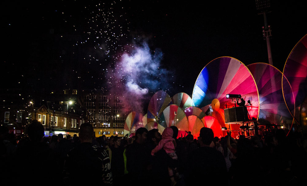 A crowd watch a group of giant colourful circles