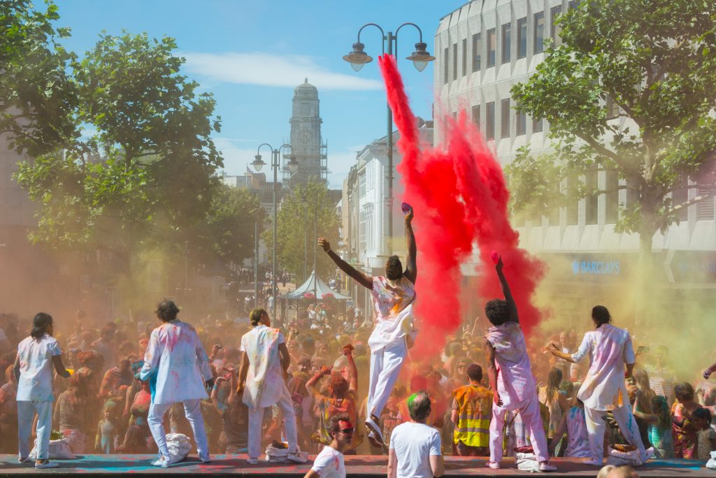 A group of performers through coloured powder over a crowd