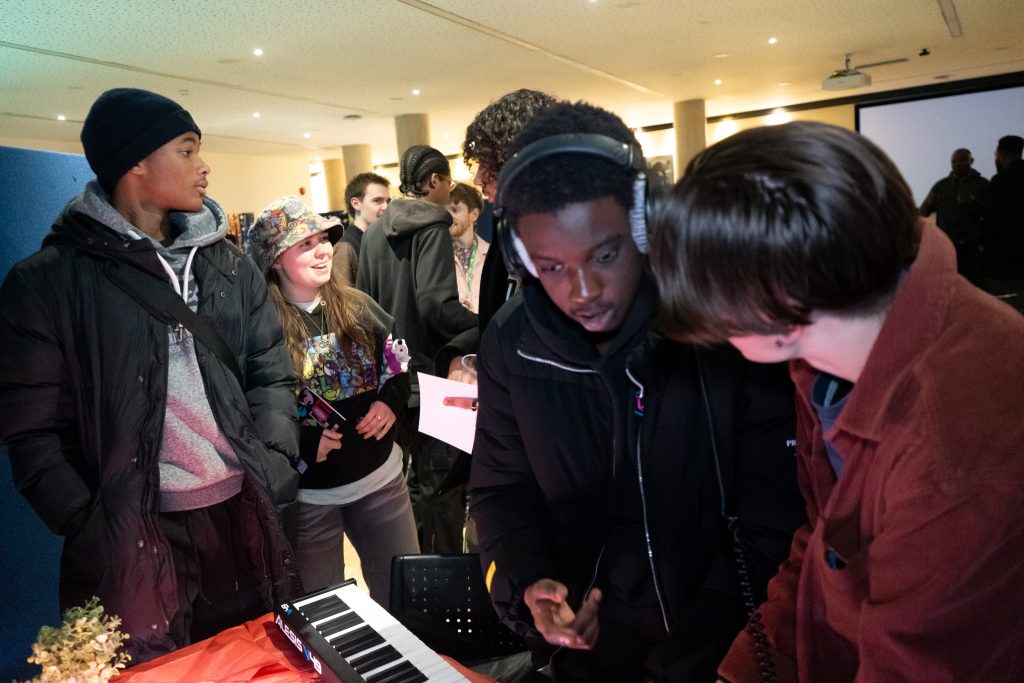 A group of people gather round a keyboard