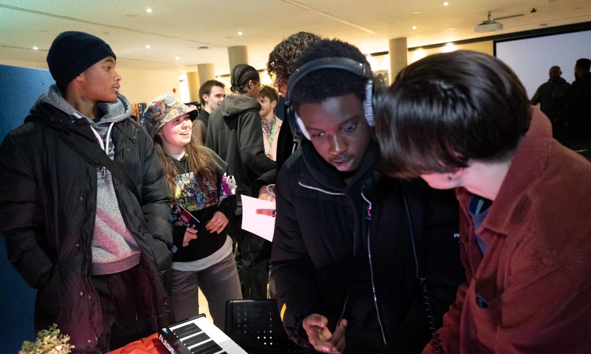 A group of people gather round a keyboard