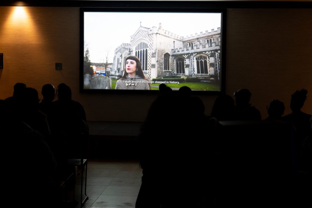 A seated audience watch a film