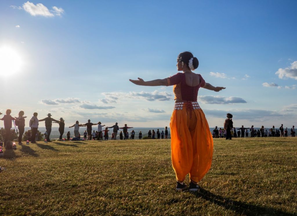 A South Asian dancer stands on a hilltop
