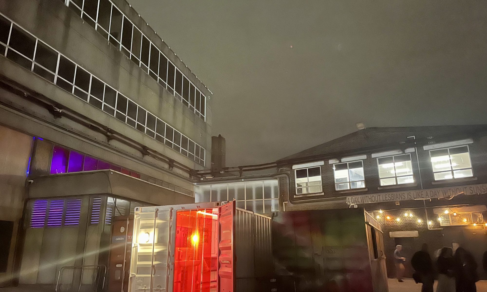 A night time shot of industrial buildings behind an illuminated porta cabin