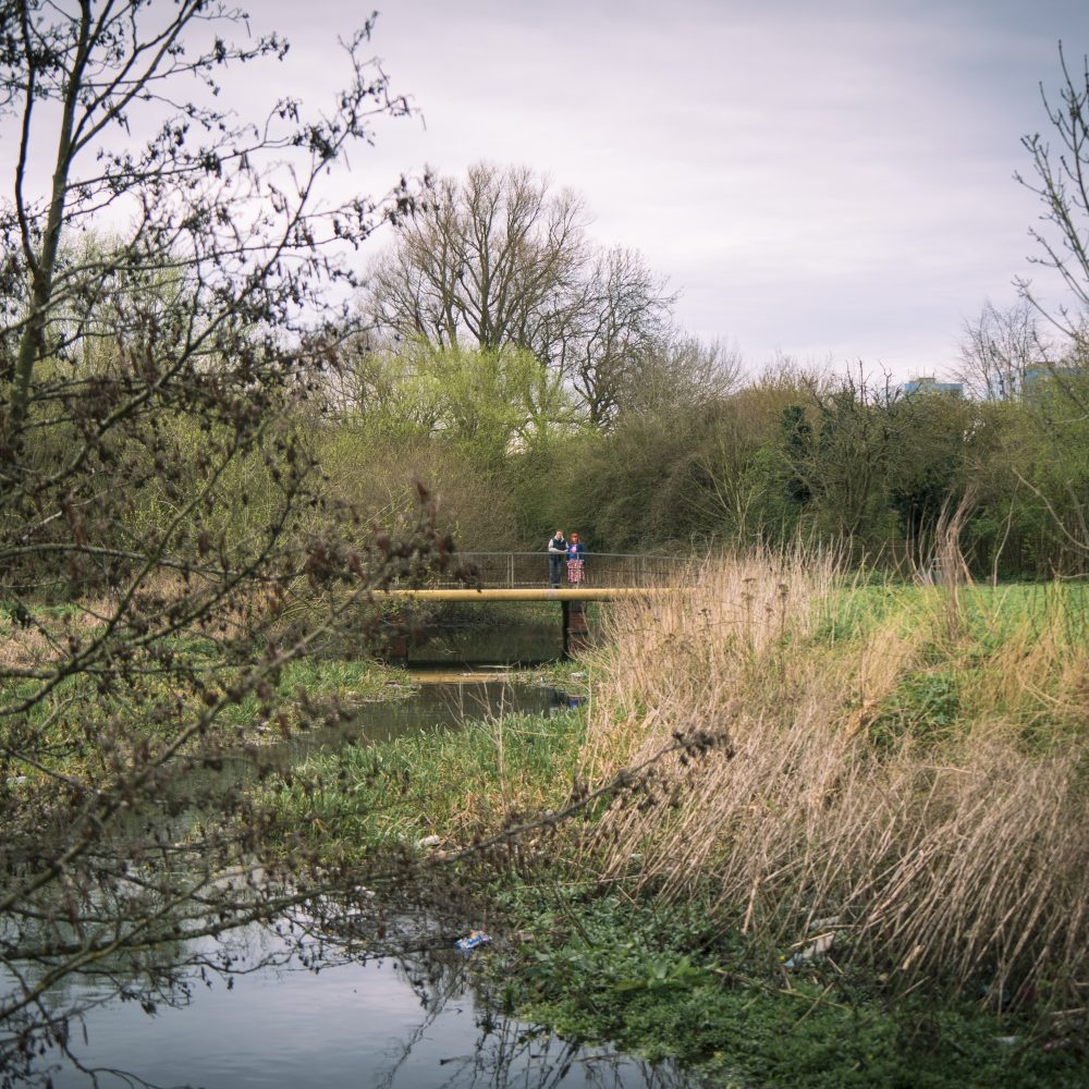 Two people standing on a bridge over a river