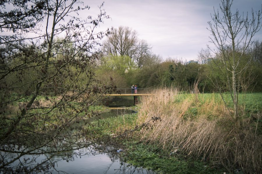 Two people standing on a bridge over a river